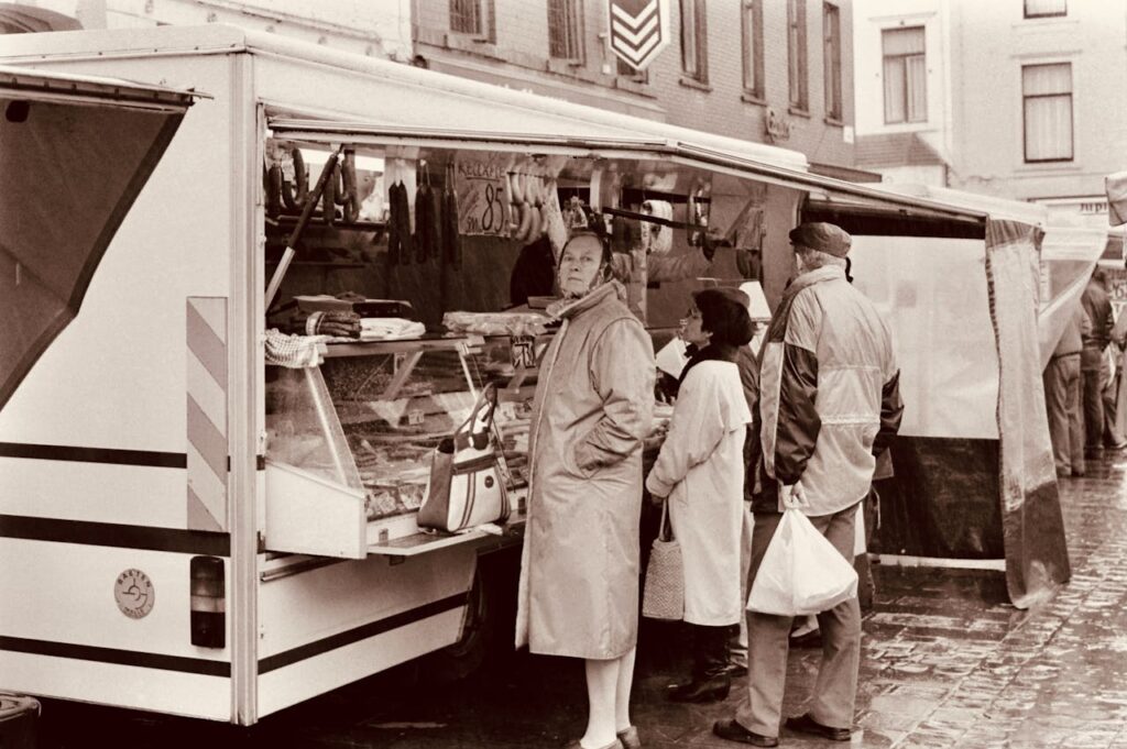 zipwp-image-15806945 Sepia Photo of People in Front of a Butchers Stall in the Market